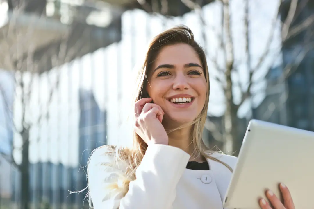 Woman talking on the phone while holding a tablet, standing outdoors